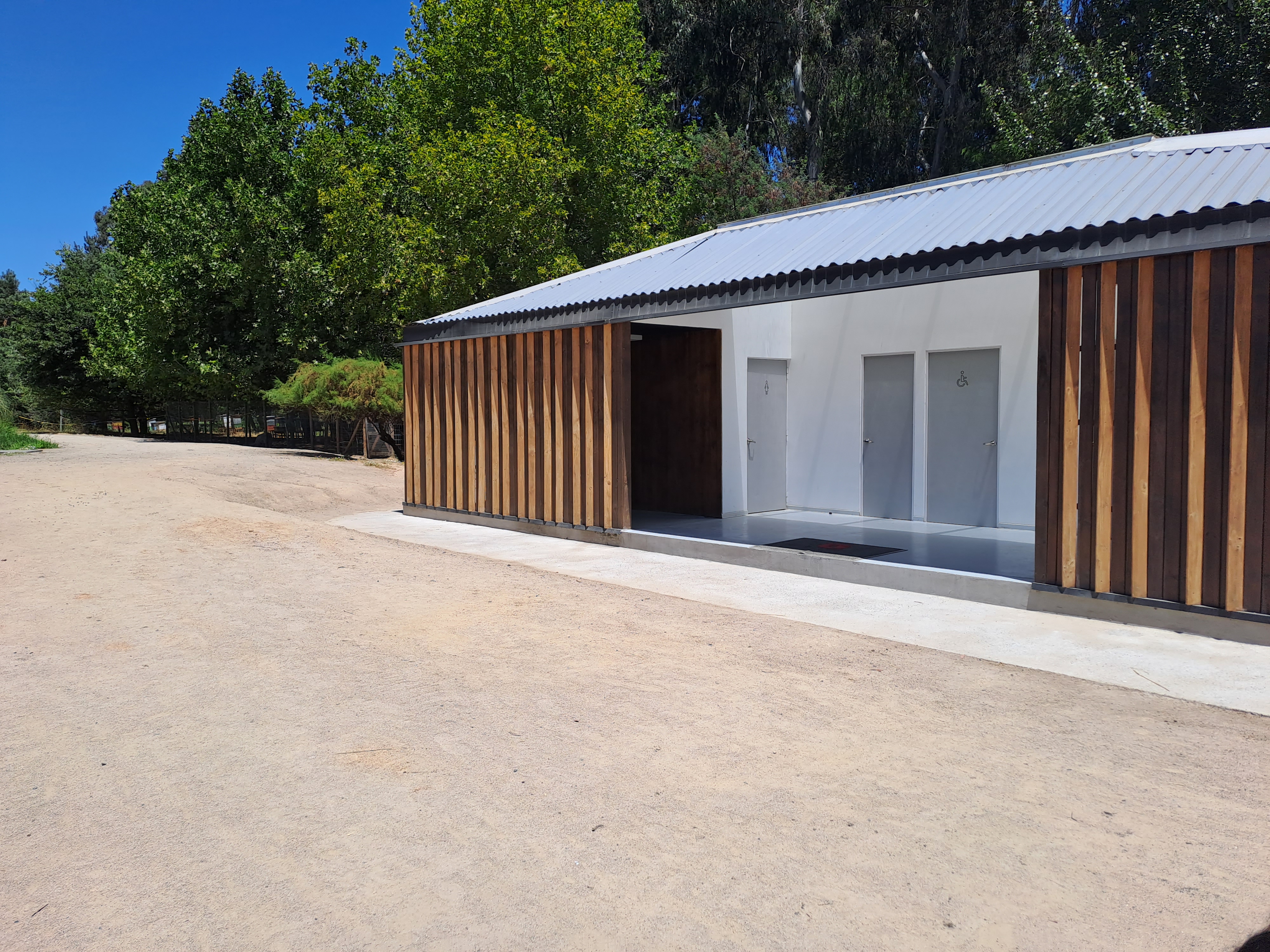 Fotogrfía del edificio techado en el que se encuentran los baños desde un ángulo más amplio, destaca el gran espacio